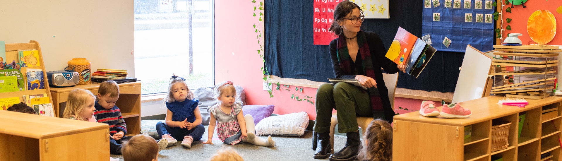 Teacher reads a book to several toddlers