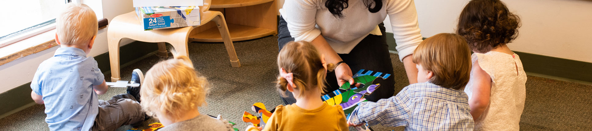 4 toddler students reading books and playing