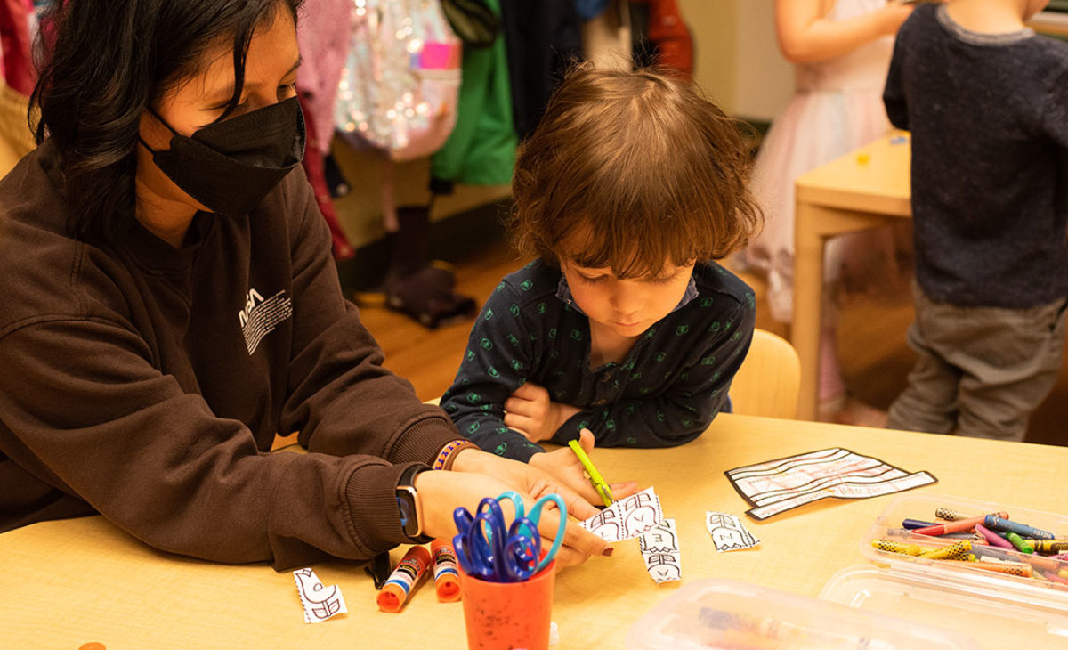 Teacher helps young students with crafts