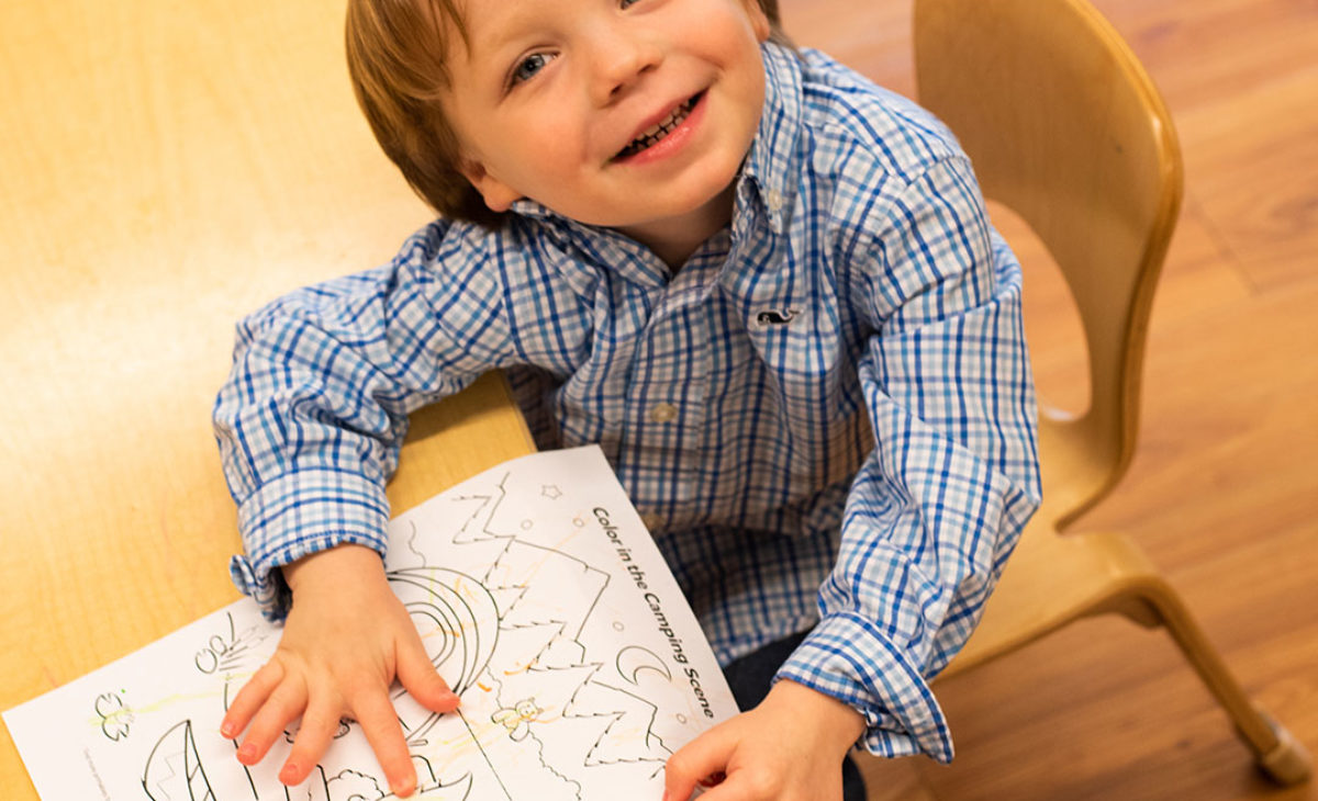 Smiling boy shows off his drawing
