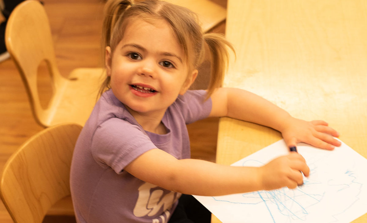 Toddler girl smiling and drawing with crayons