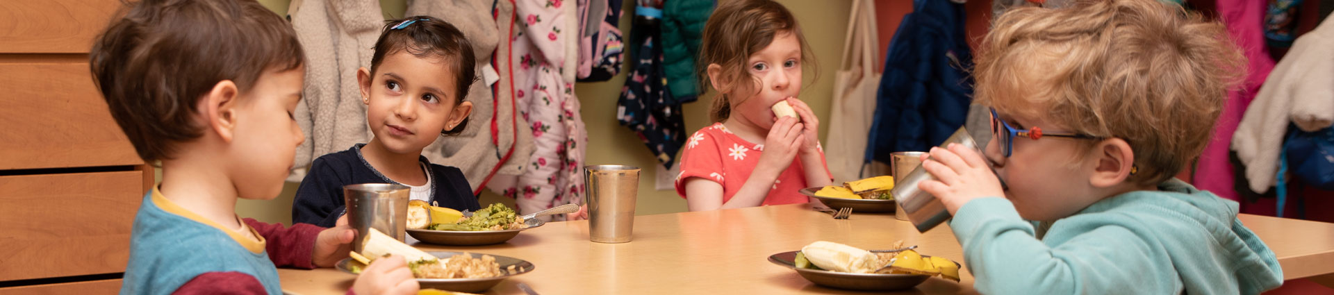 4 toddlers sitting at a table eating