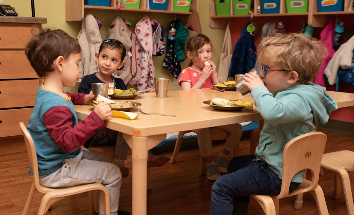 4 toddlers eating at a table together