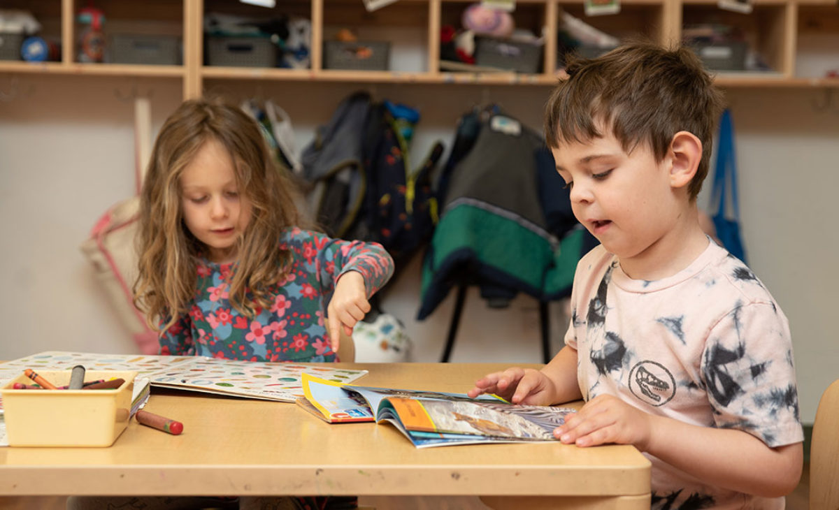 Two young students read together at a table