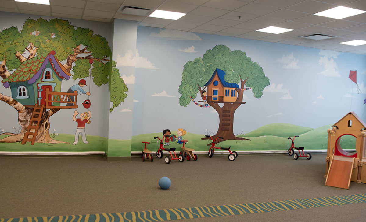 A large empty playroom with a mural on the wall