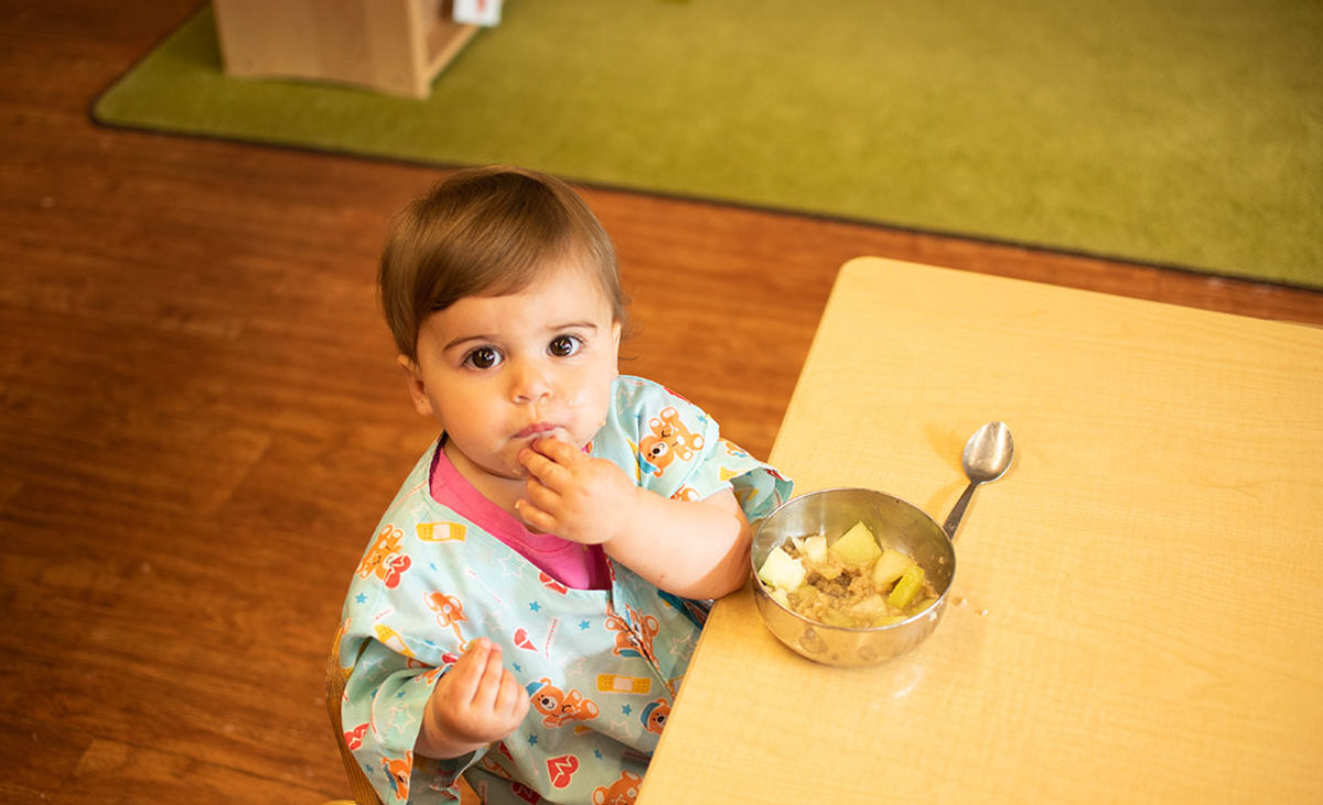 Toddler sitting at table eating a snack