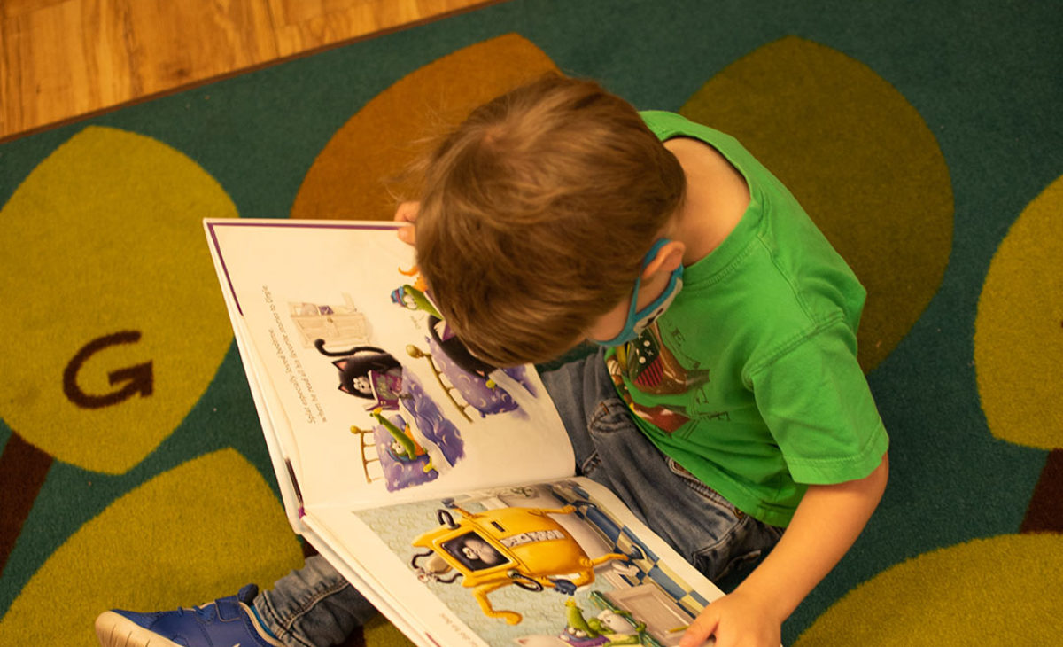 Toddler boy sitting on floor reading a book